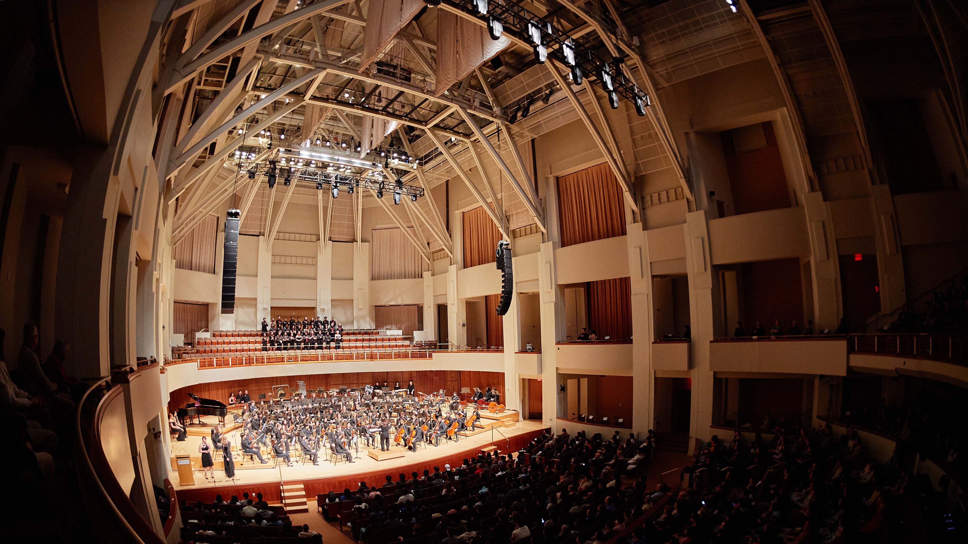 The Gamer Symphony Orchestra on stage shot from far back with ceiling beams showing.