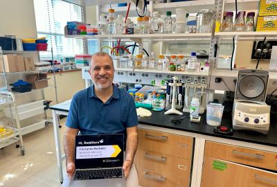Carlos Machado holding a laptop in his lab