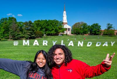Two students with Maryland Day sign on Chapel Field