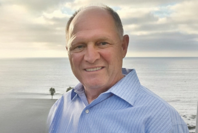 Man wearing blue button-down shirt with the ocean in the background