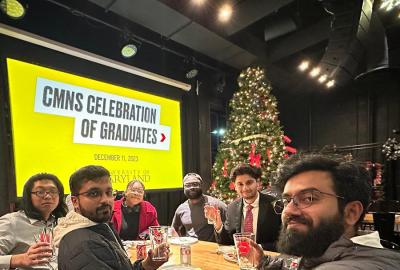 A group of 6 CMNS students at a party, lifting glasses with the SCIENCE TERP logo on them.