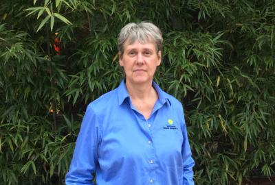 Sara Gallager in a blue Smithsonian shirt poses in front of bamboo.