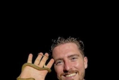 Jory van Thiel with a small non-venomous snake wrapped around his hand.