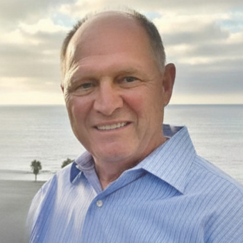 Man wearing blue button-down shirt with the ocean in the background