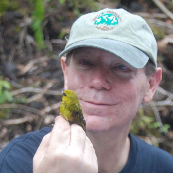 Robert Fleischer holding a little green bird in his hand