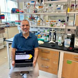 Carlos Machado holding a laptop in his lab