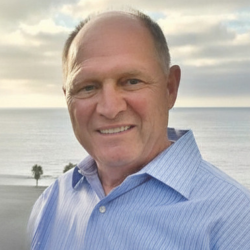 Man wearing blue button-down shirt with the ocean in the background